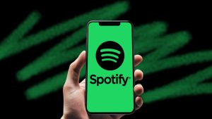 Hand holding a mobile phone with the Spotify app opened.
